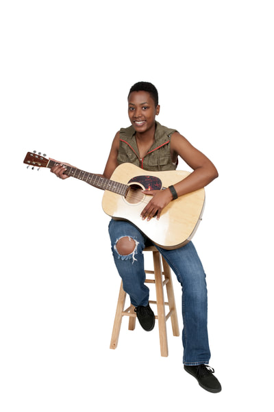 woman sitting on stool holding an acoustic guitar.